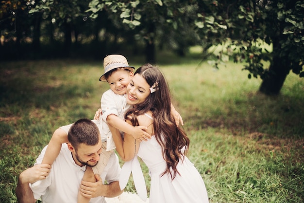 Picture of cheerful caucasian mum, dad and their child have fun together and smiles in the garden