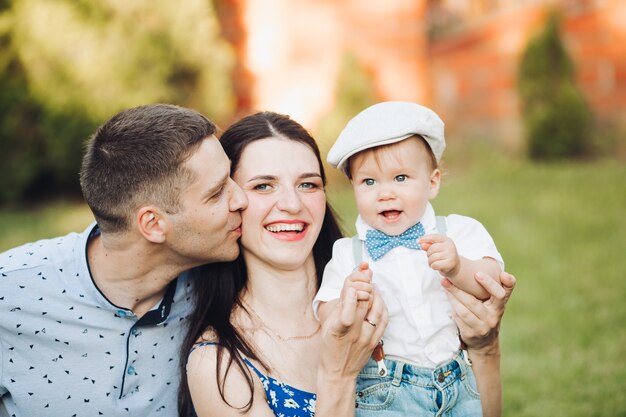 Free photo picture of cheerful young caucasian female and male holds their child on hands, smiles and rejoices