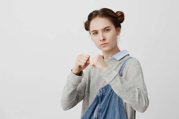 Free photo picture of concentrated woman wearing casual standing in defensive position with clutching fists. feminine girl with strict gaze ready to fight being offended with street thief. body language