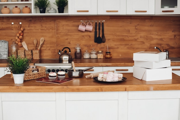 Picture of cupcakes, marshmellows, white boxes with sweets on the cupboard