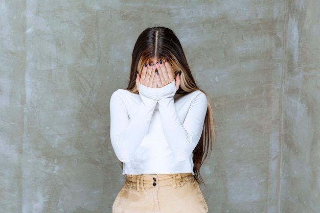 Free photo picture of a cute girl model standing and closing face with hands