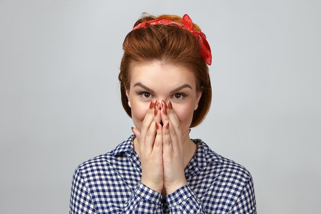 Picture of emotional beautiful young lady in fashionable clothes covering mouth, amazed with unexpected gift from boyfriend