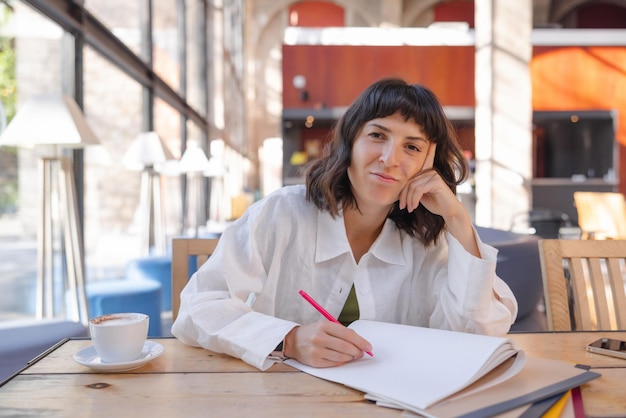 Picture of emotional woman looking at camera with notebooks