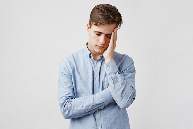 Picture of exhausted young man in blue casual shirt.