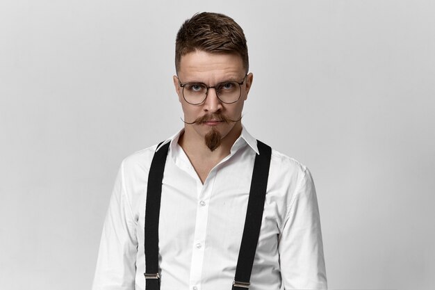 Picture of fashionable young bearded male college teacher wearing eyeglasses, suspenders