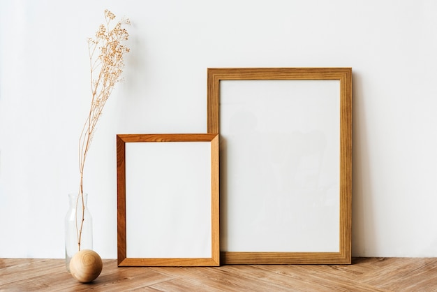 Picture frames on a wooden sideboard table with dried flowers