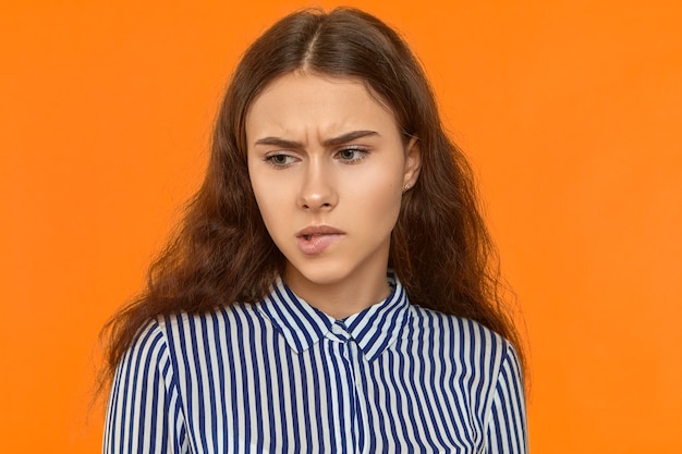 Free photo picture of frustrated pensive student girl frowning and biting her lower lip having worried thoughtful facial expression