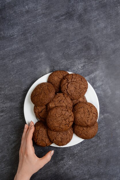 Picture of hands holding chocolate cookies over wooden surface