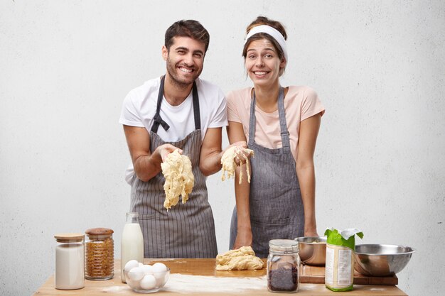 幸せな楽しい女性と男性の写真はパンを焼くための生地を準備します