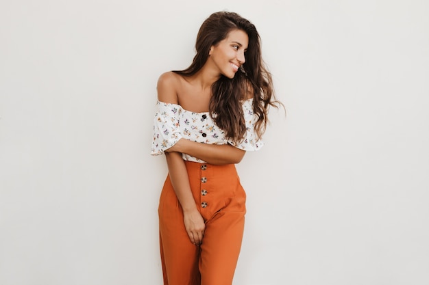 Picture of lady in orange trousers with high waist and white top with floral print