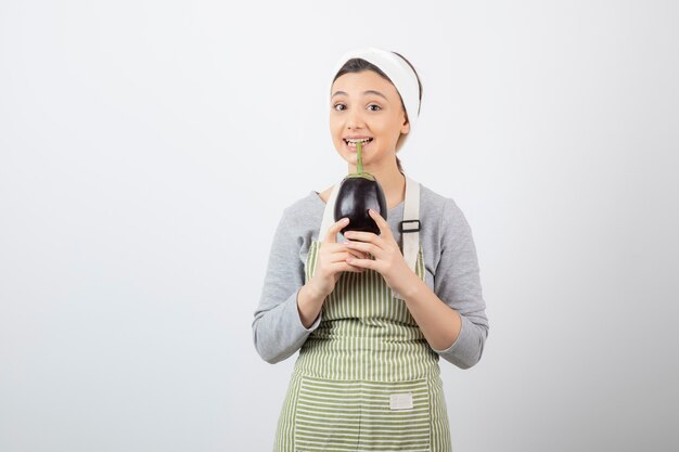 Picture of a nice young woman model in apron holding an eggplant