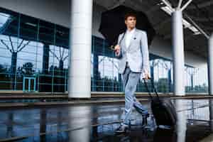 無料写真 黒い傘と空港で雨の中歩いてスーツケースを保持していると兄弟分青年実業家の画像