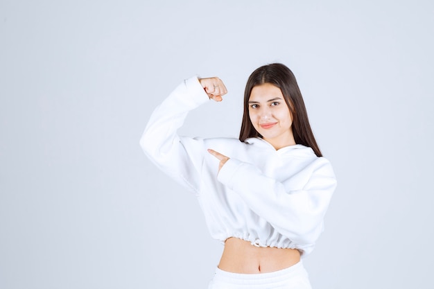 Picture of a positive young girl model pointing at her bicep.