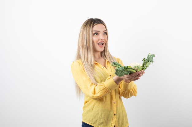 Picture of a pretty woman model standing and holding cauliflower in hand.