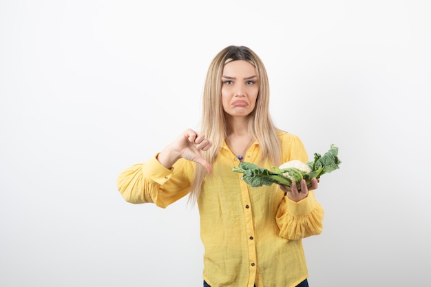 Picture of a pretty woman model with cauliflower showing a thumb down.