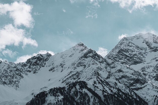 Picture of rocky mountains covered in the snow under a cloudy sky and sunlight