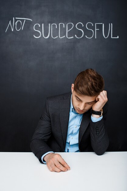 Picture of a sad man over black board with text not successful