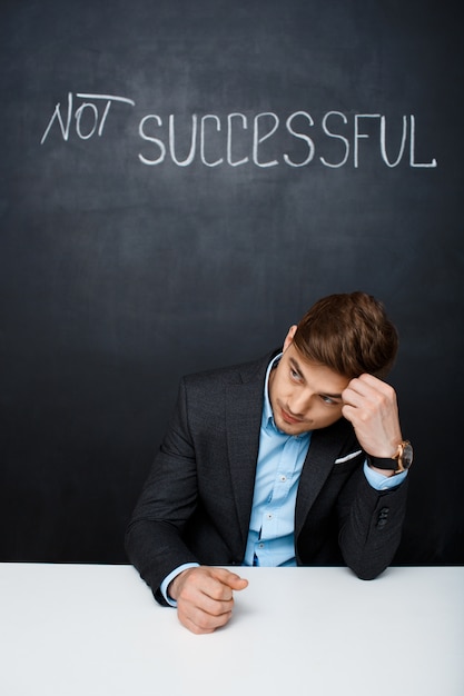 Free photo picture of a sad man over black board with text not successful