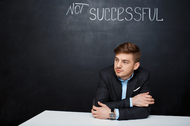 Free photo picture of a sad man over black board with text not successful