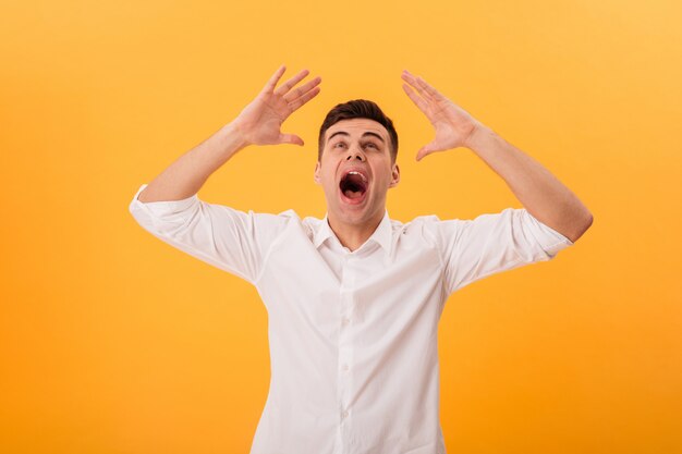 Picture of screaming man in white shirt looking up over yellow 