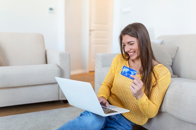 Immagine che mostra la donna graziosa che acquista online con la carta di credito donna che tiene la carta di credito e utilizza il computer portatile concetto di acquisto online