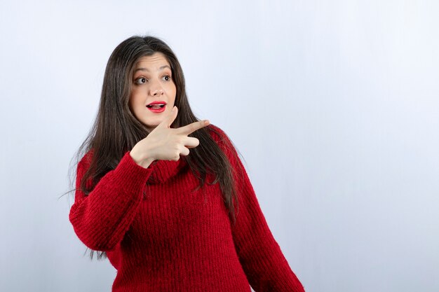 離れて指している赤いセーターの笑顔の若い女性の写真