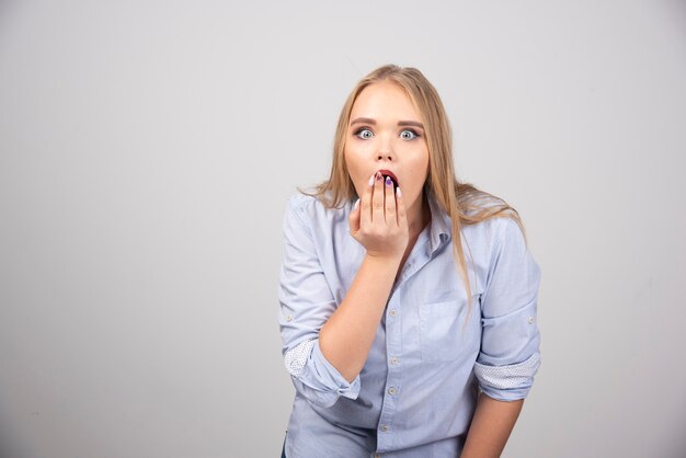 Picture of surprised female slightly covering round open mouth with hand.