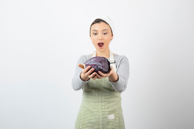 Фотография удивленной женщины, смотрящей на фиолетовую капусту на белом