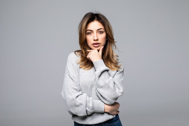 Picture of thoughtful woman dressed in sweater posing over grey wall and looking aside to copyspace