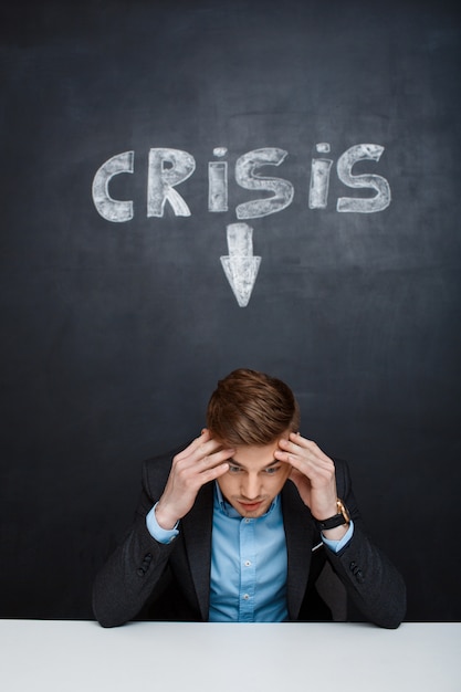 Picture of tired man over blackboard with crisis inscription