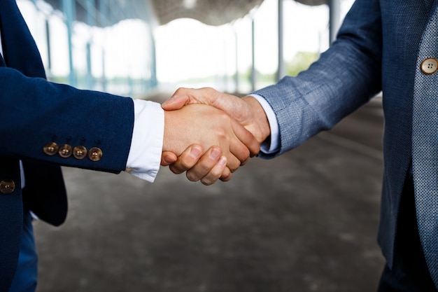 Free photo picture of  two young businessmen on street  shaking hands