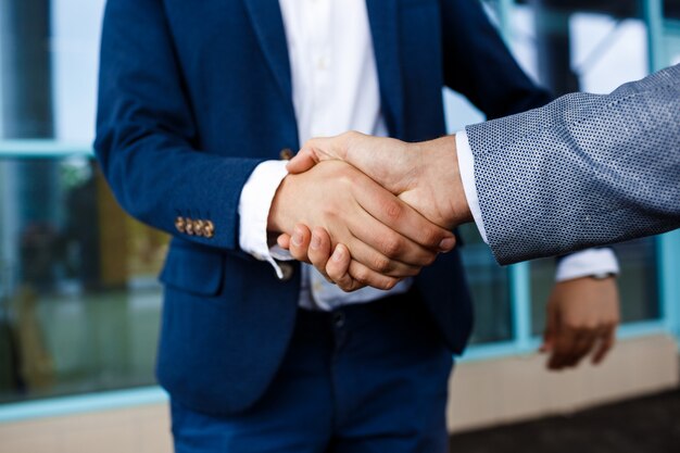 Picture of  two young businessmen on street  shaking hands