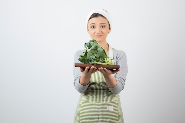 Immagine di una giovane donna attraente che tiene un piatto di legno di broccoli