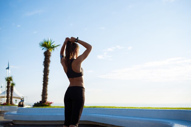 Picture of young beautiful fitness girl makes sport exercises with sea