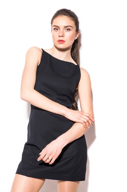 A picture of a young beautiful woman in a black dress posing over white background
