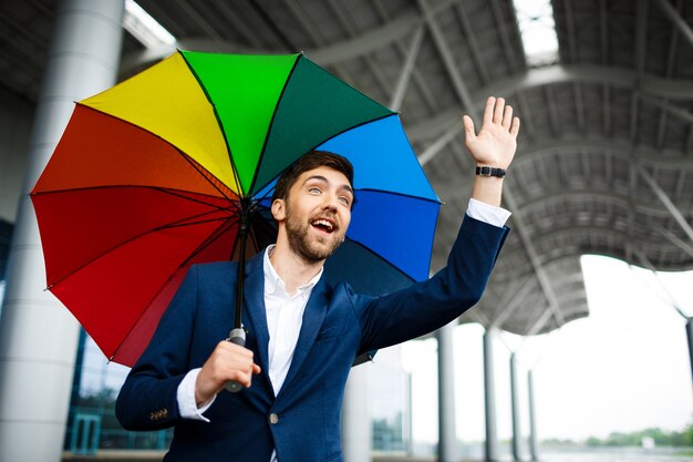 ハイタッチを示すカラフルな傘を保持している青年実業家の画像
