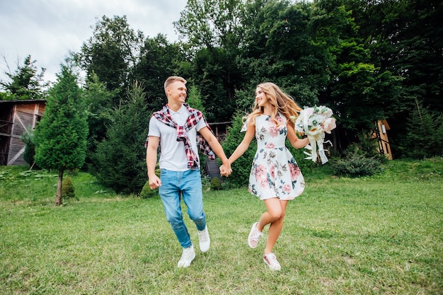 Picture of a young couple holding hands and running through the park. Enjoying the nature.