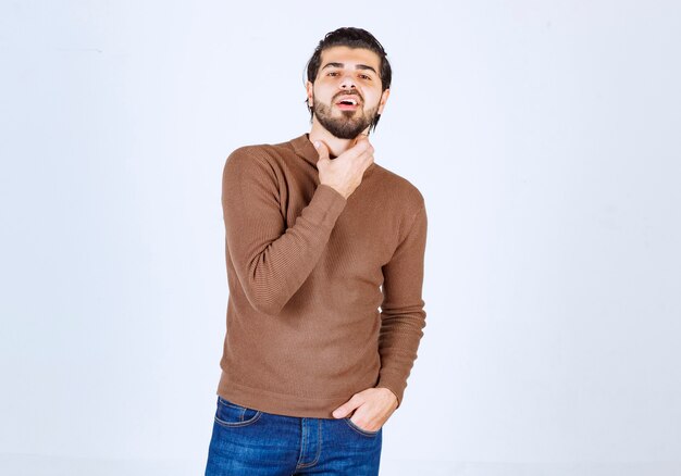 Picture of a young handsome man model standing and posing over white wall. High quality photo