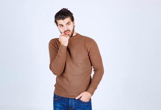 Picture of a young handsome man model standing and posing over white wall. High quality photo