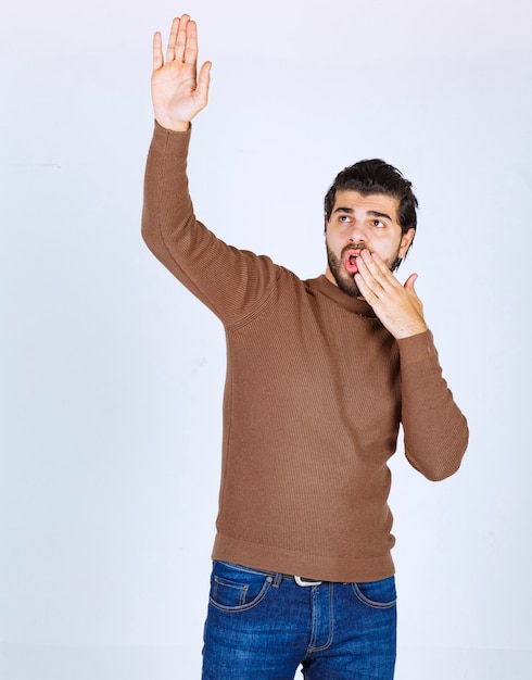 Picture of a young handsome man standing and raising a hand. High quality photo