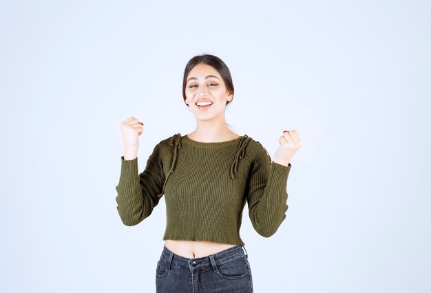 Изображение модели молодой счастливой женщины стоя и поднимая руки.