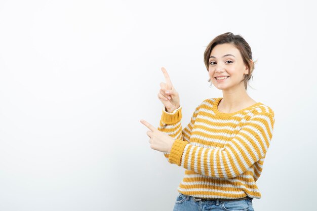 Picture of a young pretty woman model standing and pointing up . High quality photo