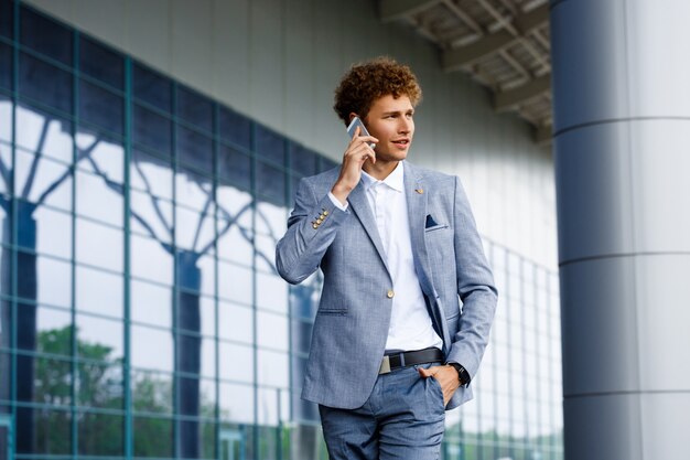 Picture of young redhaired businessman  talking on phone looking aside