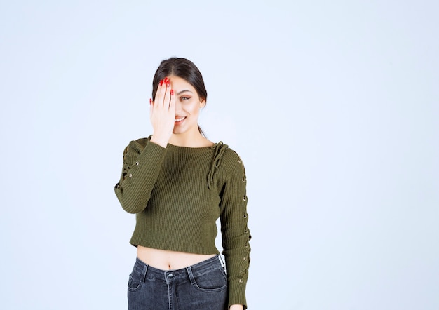 Free photo picture of a young smiling woman model covering an eye with a hand