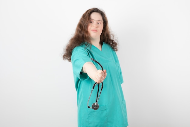 Picture of a young woman in green uniform holding stethoscope .