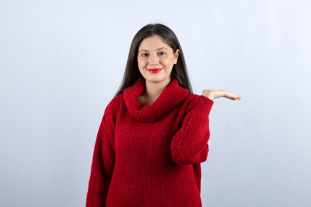 Picture of a young woman in red sweater showing hand on white background 