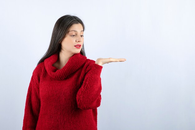 Picture of a young woman in red sweater showing hand on white background 
