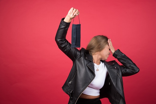 Foto gratuita immagine di una giovane donna che mostra una maschera medica nera