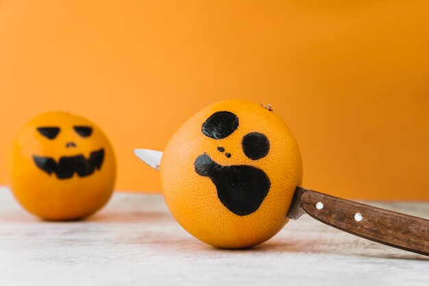 Pictured citrus with knife within and another orange on background