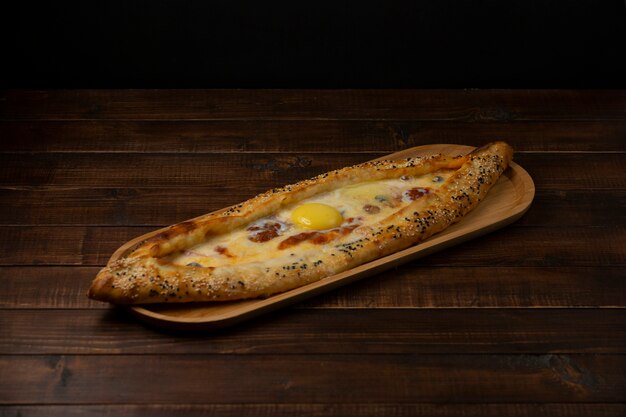 pide with sausage cheese and olive served in wood serving board